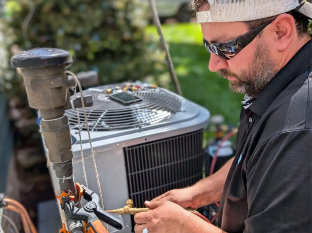 Full Time Heating & Cooling technician servicing an outdoor air conditioning unit in the West Metro